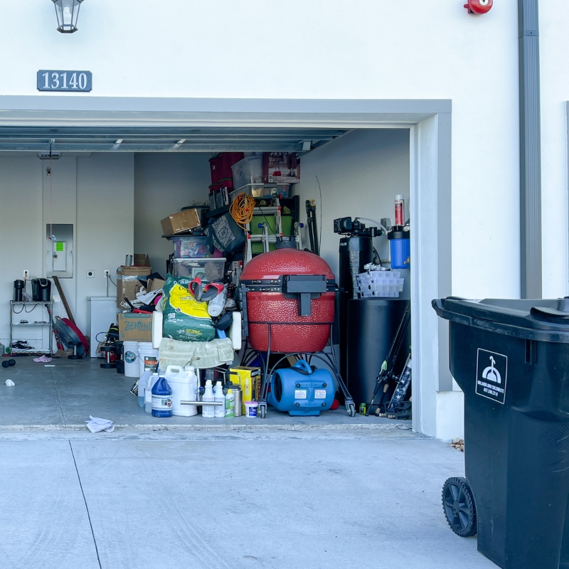 An unorganized garage filled with a lot of stuff in a neighborhood